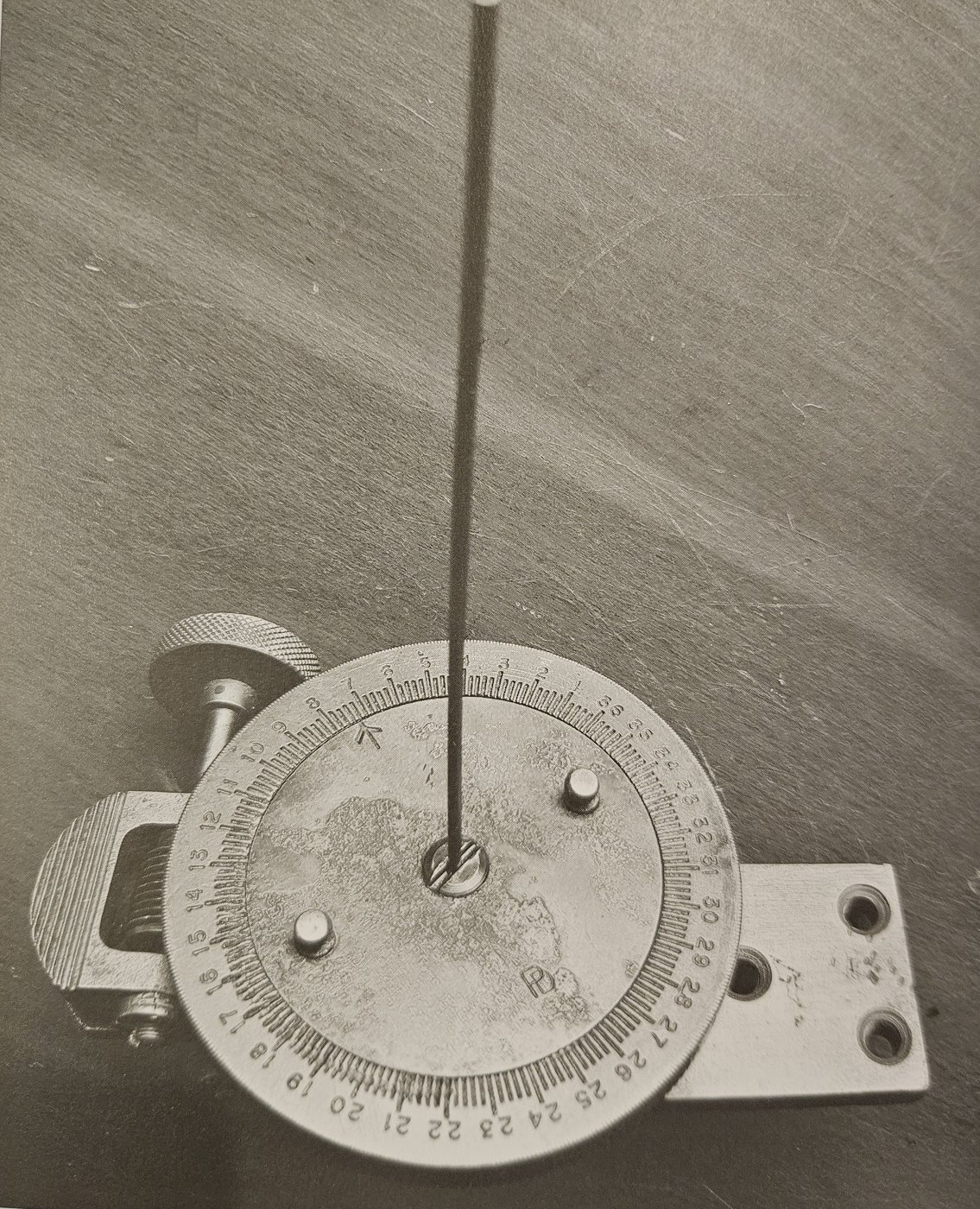 A close view of the sun compass card, graduated through the full 360 degrees, with the central spindle and shadow-wire