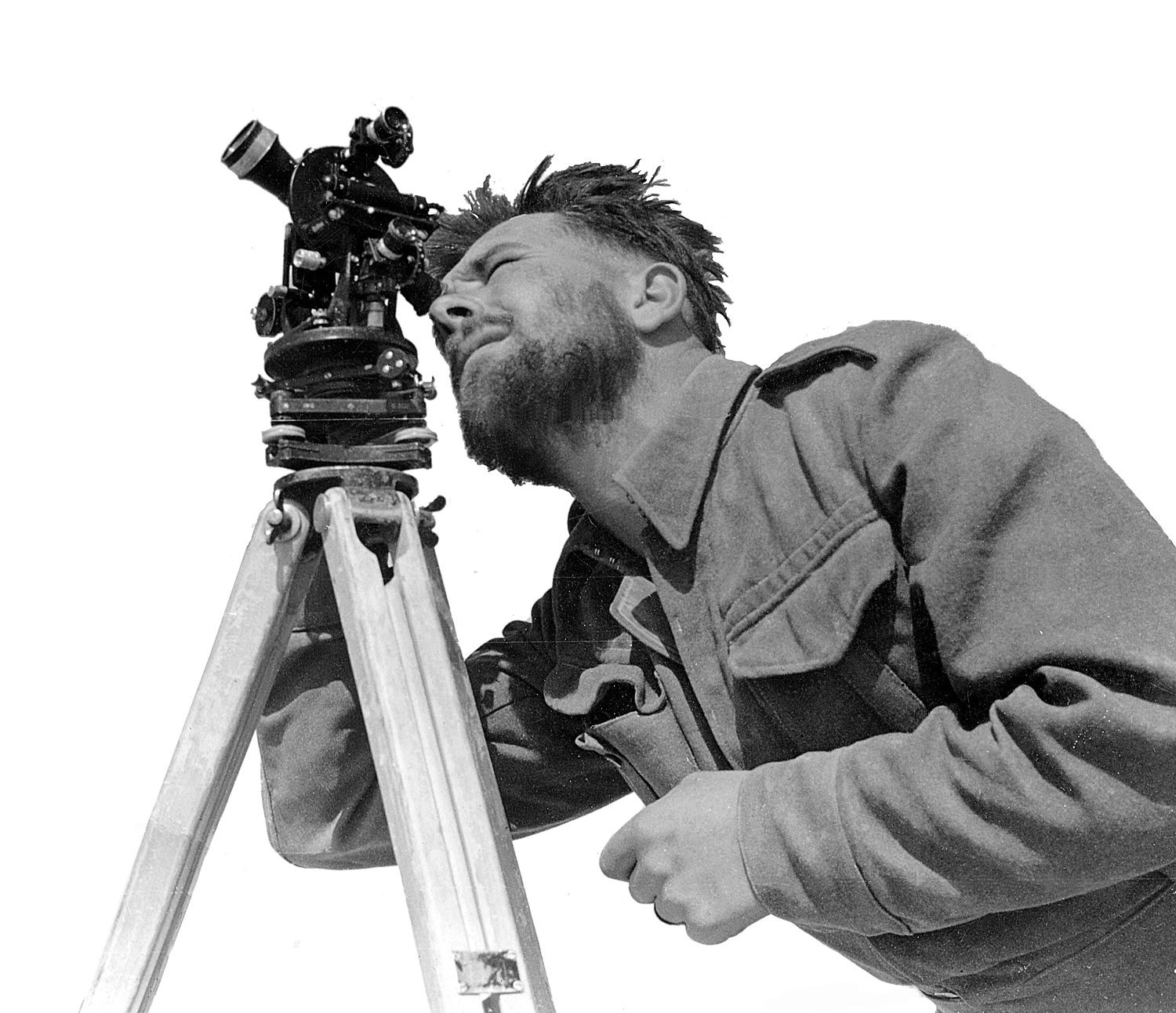 A bearded LRDG man sighting through a theodolite in the desert