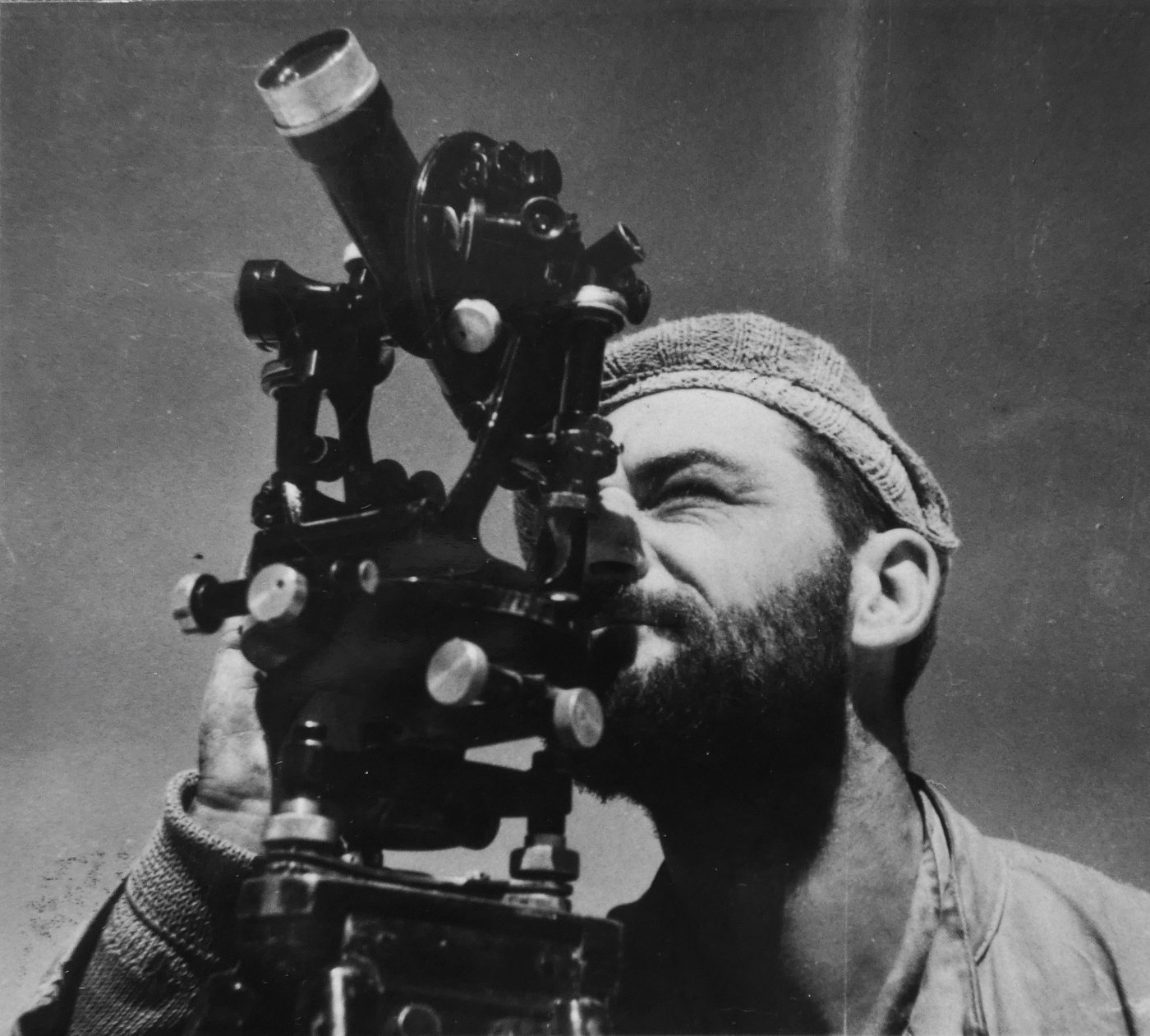 A bearded LRDG navigator taking a sight through a theodolite