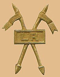 A metal badge: two crossed lances behind a rectangular plate.